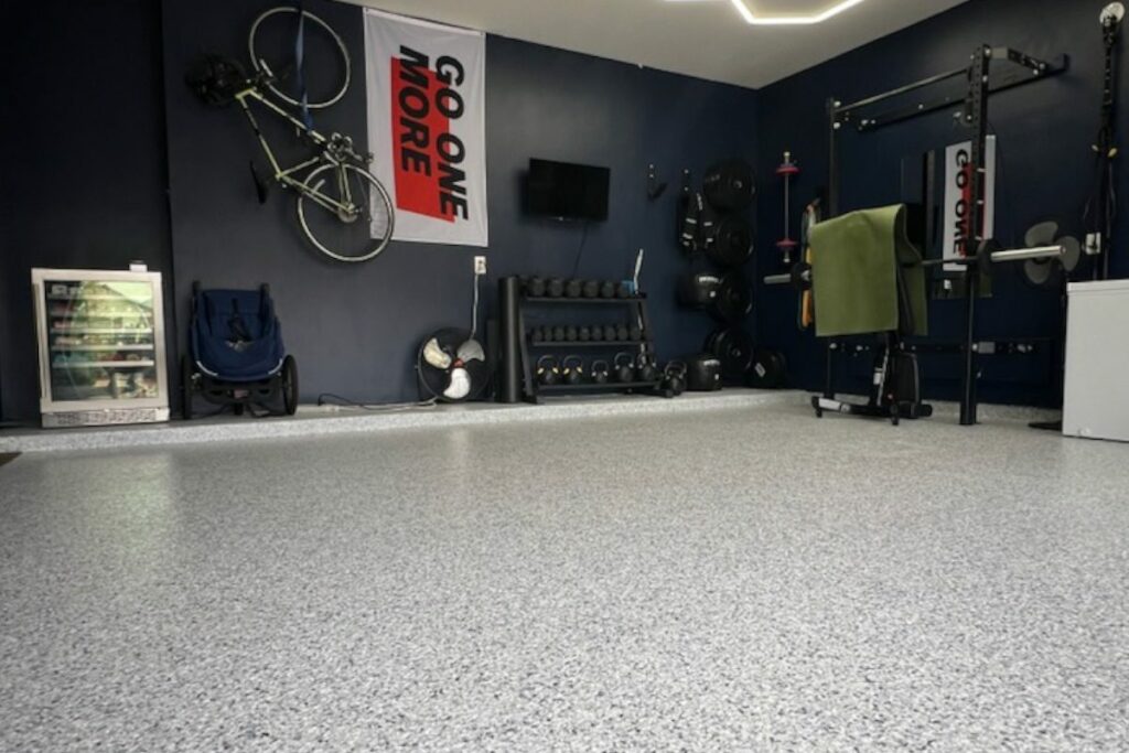 Gray speckled flake floor in a home gym with a lifting rack and a bike on the wall
